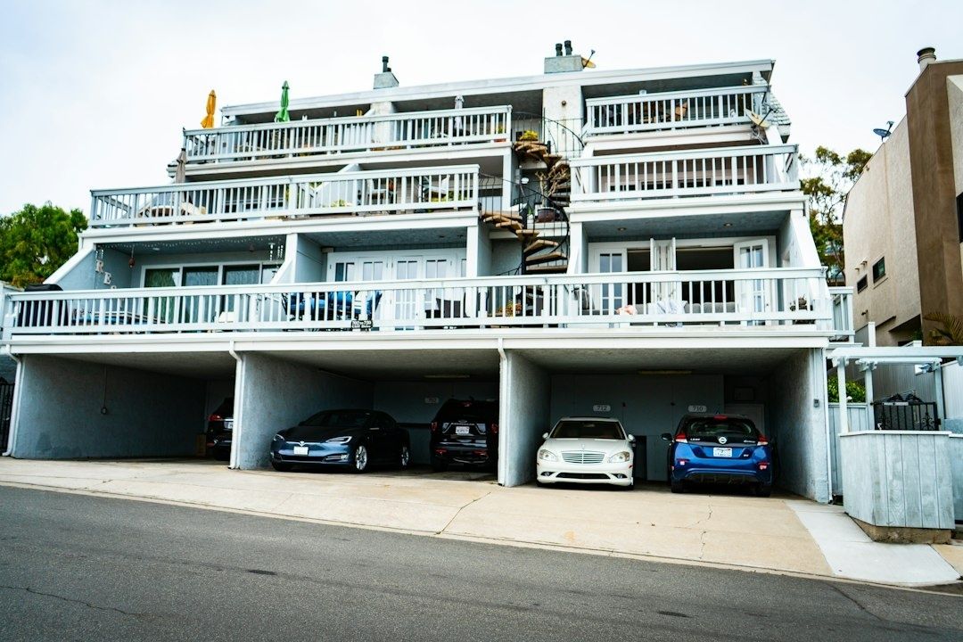Flerbostadshus med balkonger och parkerade bilar i garageplatser